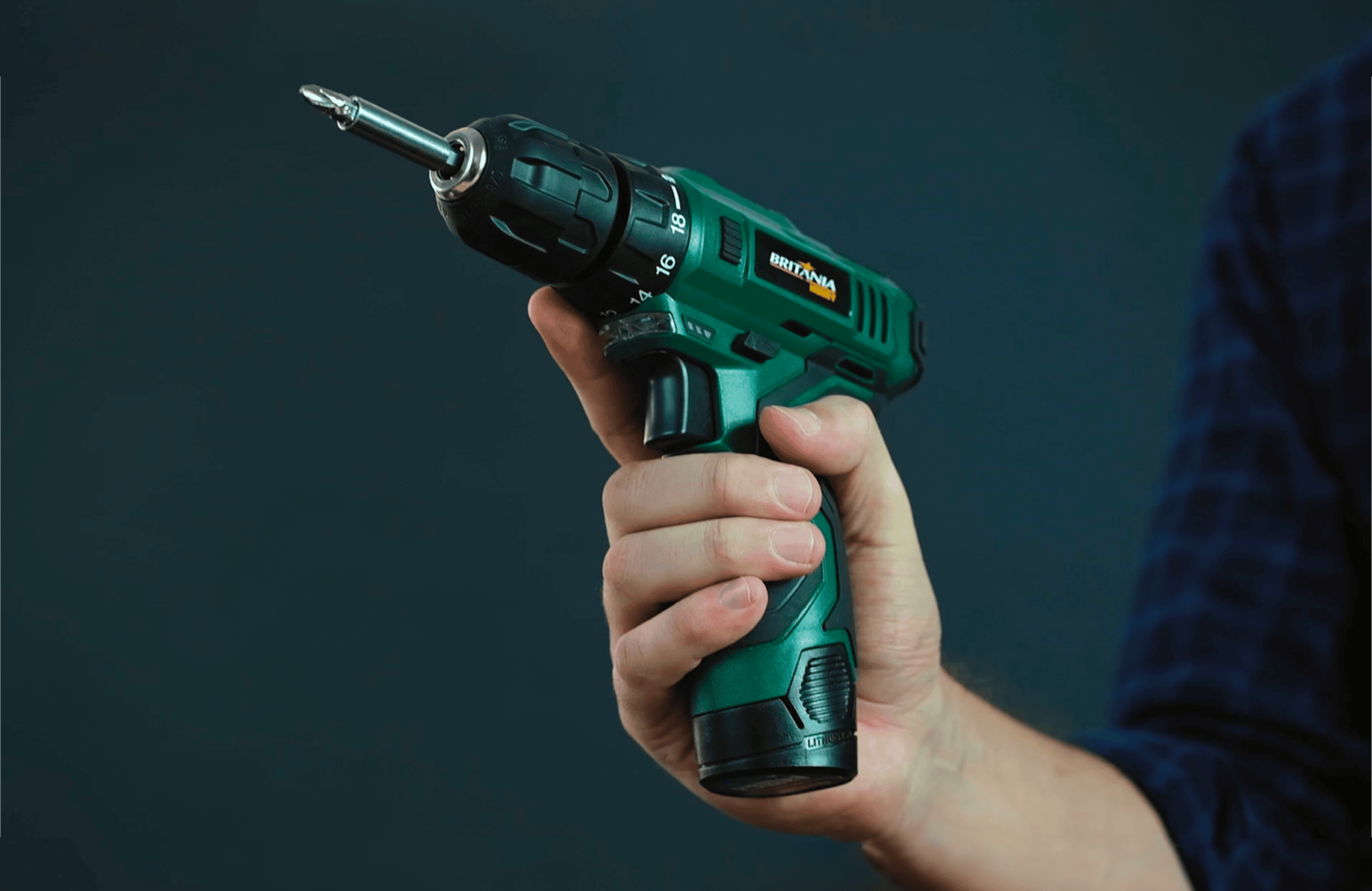 Parafusadeira Britânia na cor verde, sendo segurada por uma pessoa. A ferramenta está em destaque em diversos ângulos, mostrando seus detalhes, como o botão de ajuste de velocidade e a empunhadura ergonômica. O fundo escuro contrasta com o verde vibrante da parafusadeira, ressaltando sua robustez e design moderno.