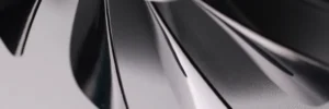 Hélice de ventilador em close-up, mostrando pás de metal com acabamento escuro e formato curvo, destacando resistência e design para ventilação mais intensa.