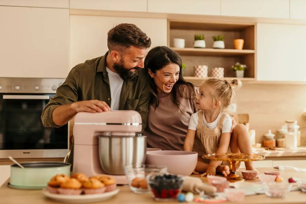 Família aproveitando o tempo juntos fazendo cupcakes em uma cozinha moderna e brilhante