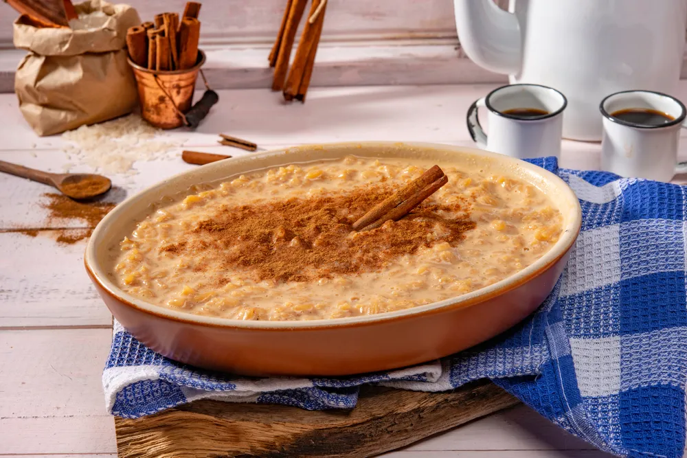Arroz doce com canela em tigela marrom em ambiente rústico, comida tradicional brasileira.