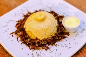 Cuscuz recheado com queijo, carne seca desfiada e manteiga em uma panela