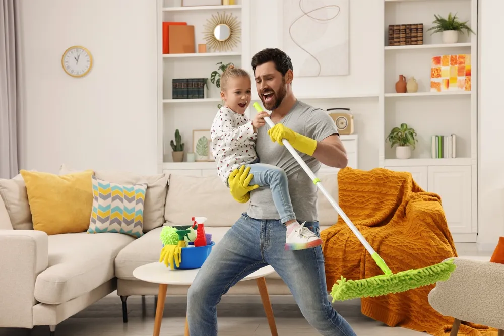 Faxina de primavera. Pai e filha cantando enquanto arrumam a casa juntos.
